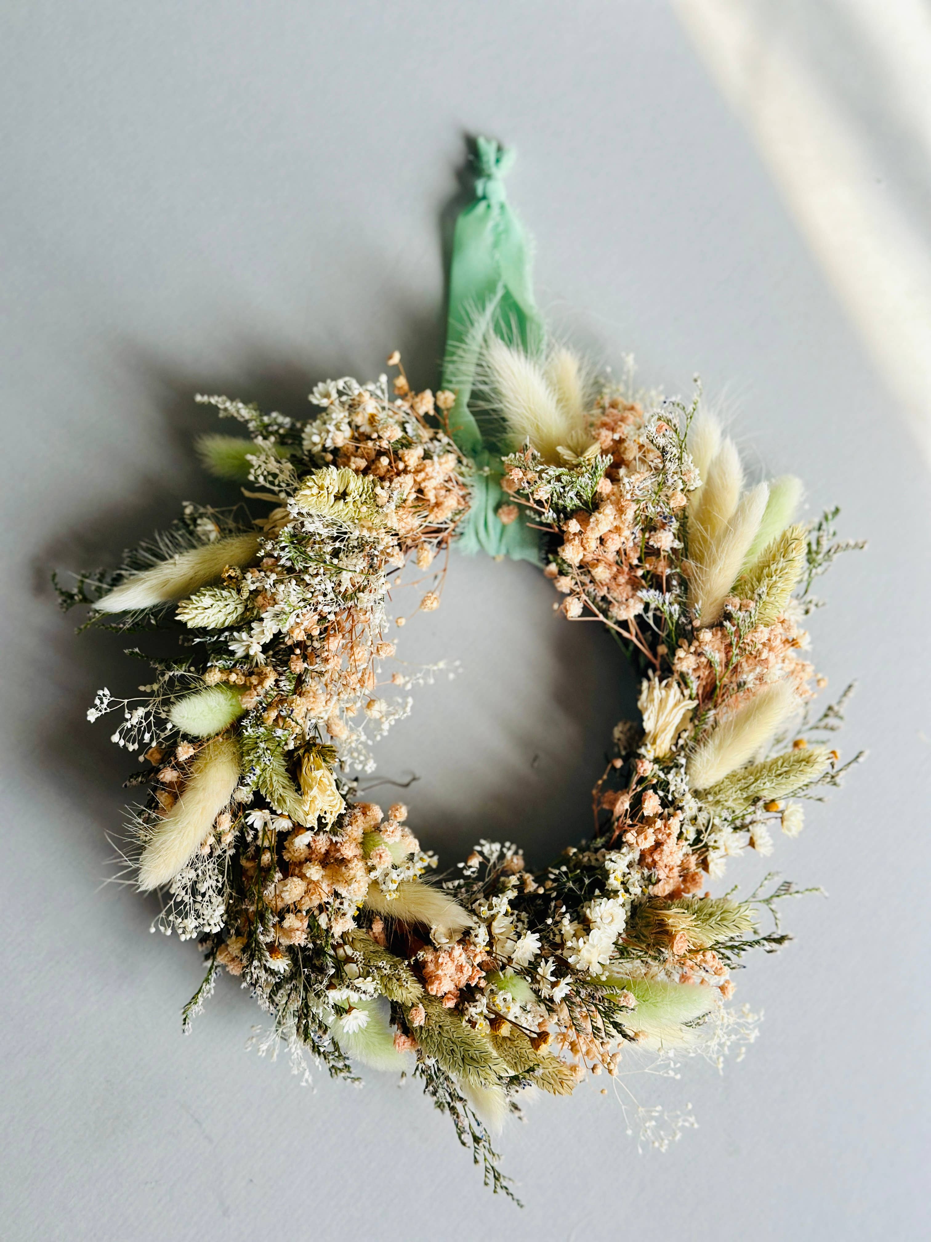 Decorative wreath with greenery and flowers on a light gray background